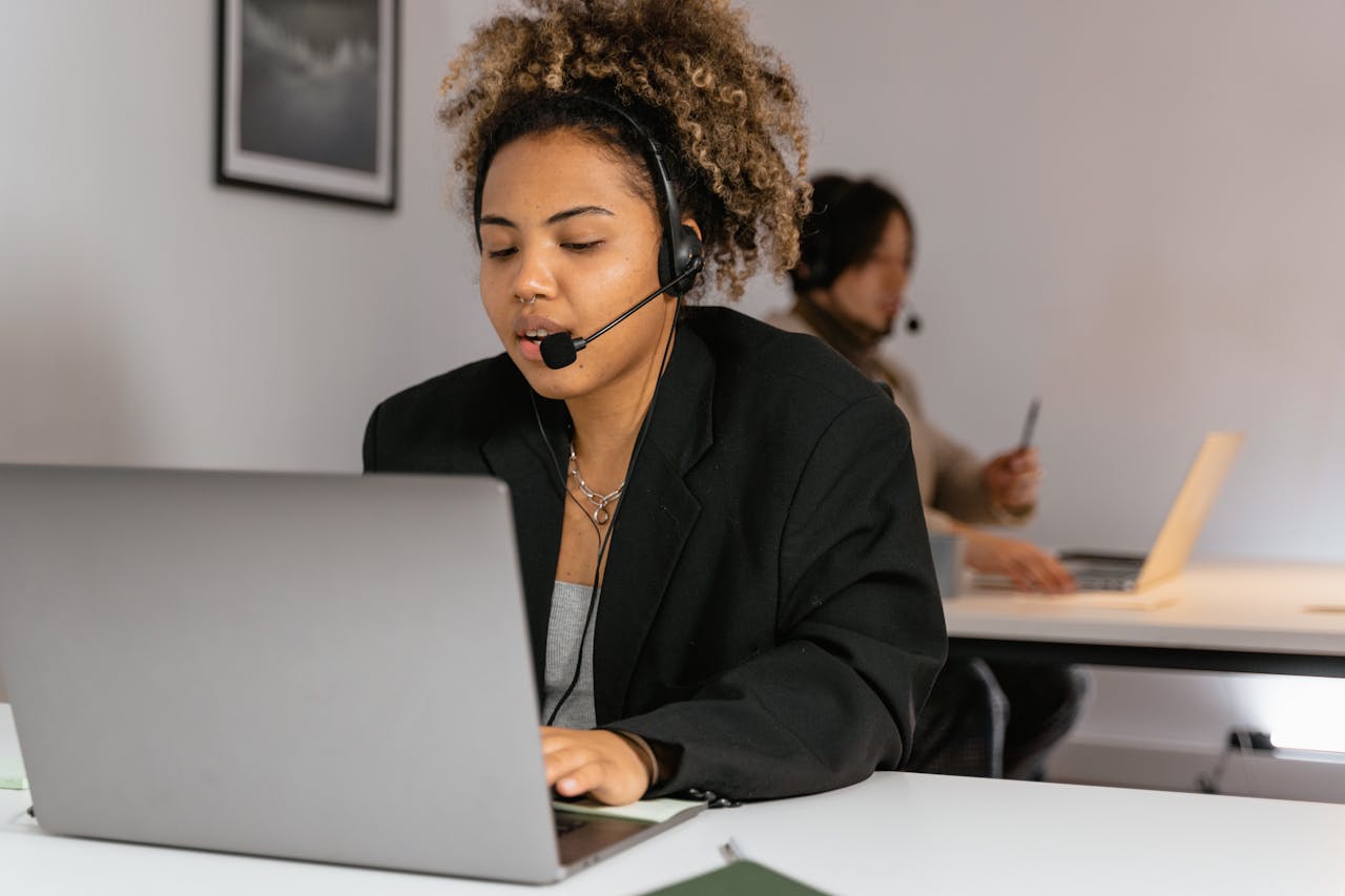 hero-img-02 African American woman working in customer support with a headset and laptop.